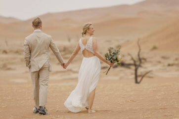 Romantic couple’s portrait against the muted tones of the Namib Desert dunes on an overcast day