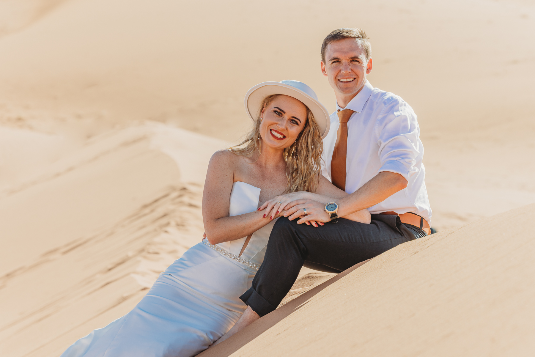 couple sitting on the dunes after eloping in deadvlei, image by mariette du toit photography
