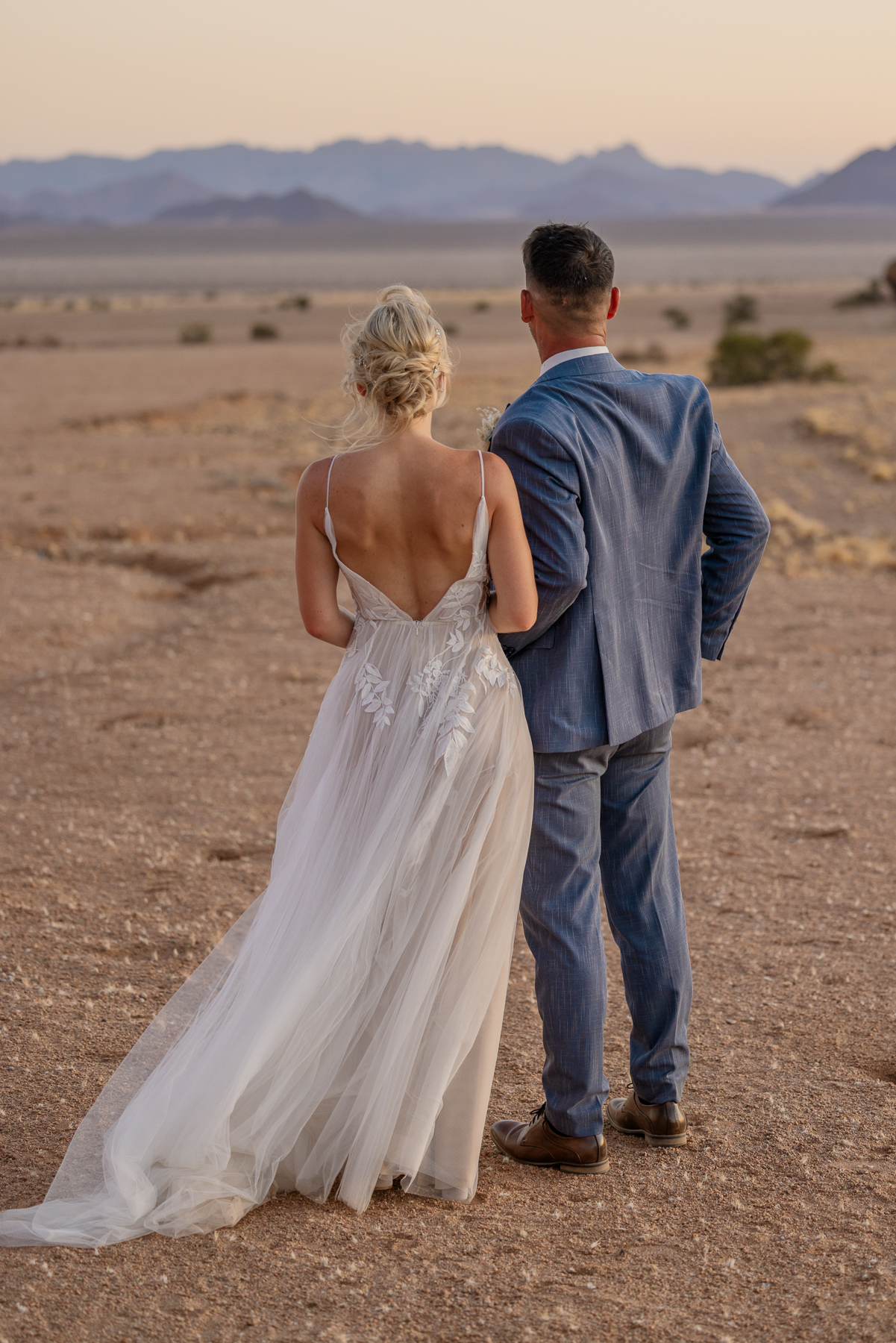 Bride and groom looking out over the desert plains and mountains near Sossusvlei