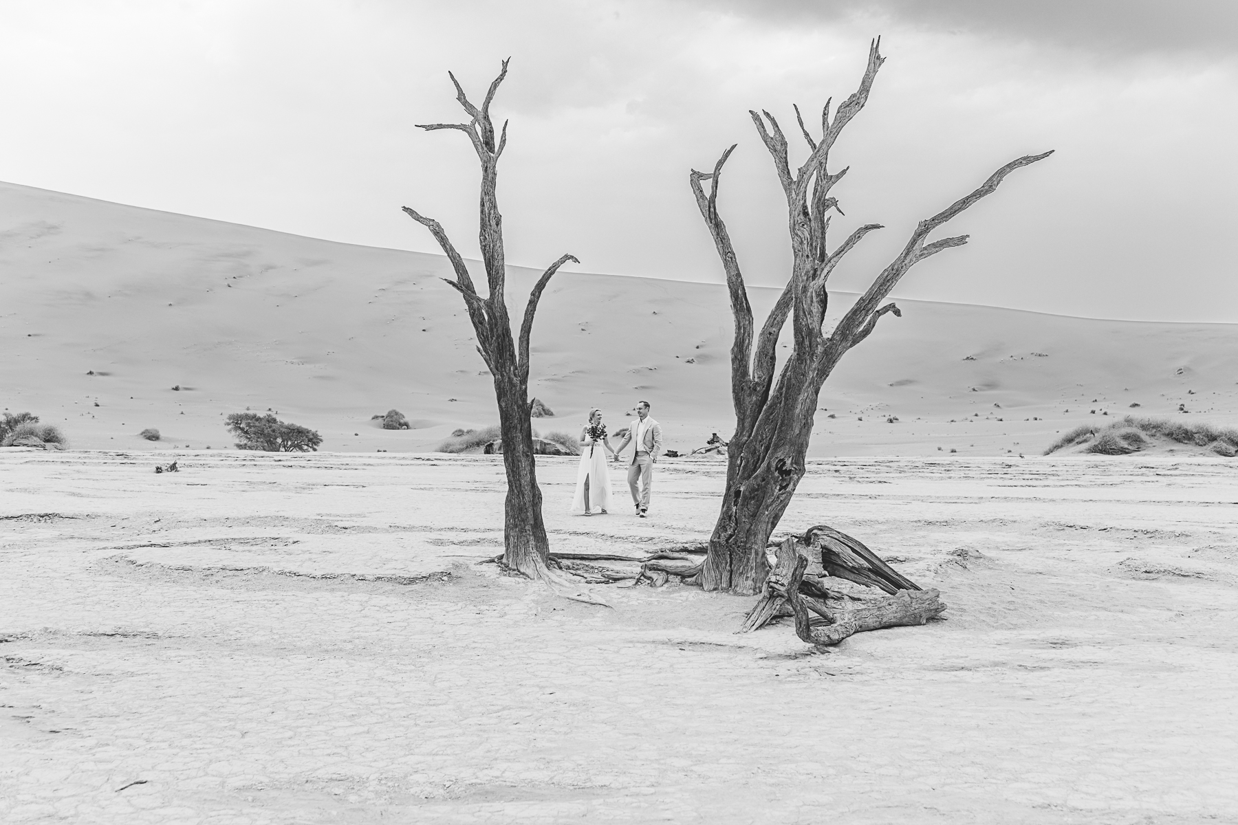 black and white image of couple walking in deadvlei, namibia during elopement