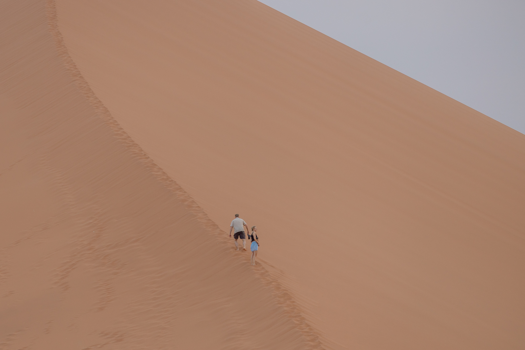couple climbing dune 45, sossuslvei at sunset