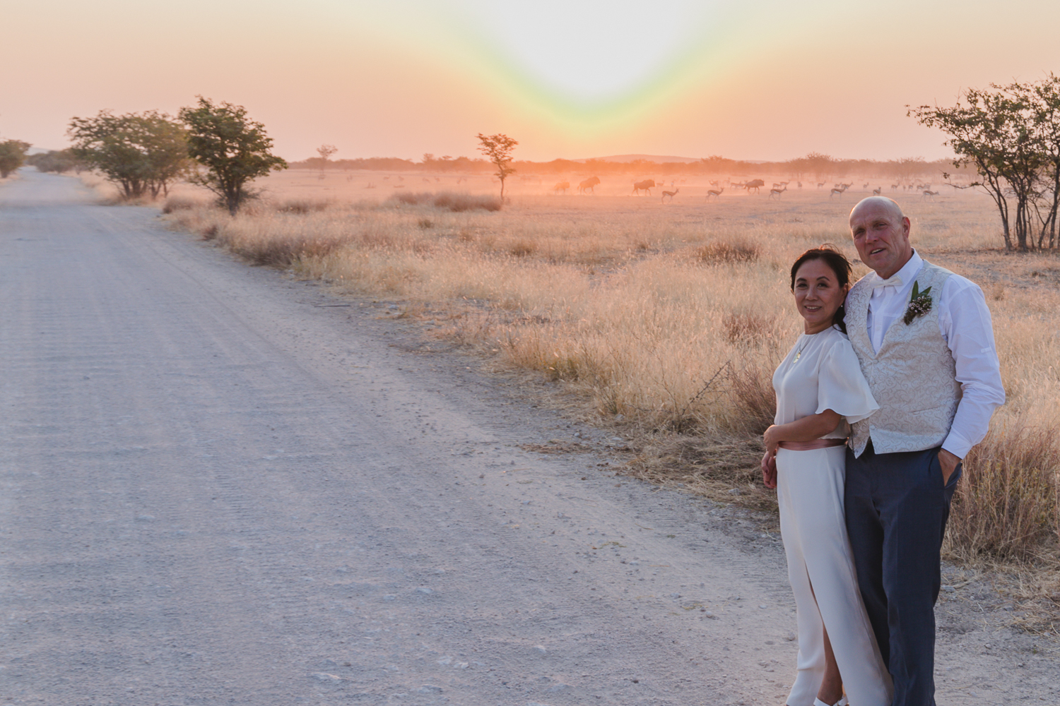 Couple beside a gravel road in the Namibian bushveld at sunset