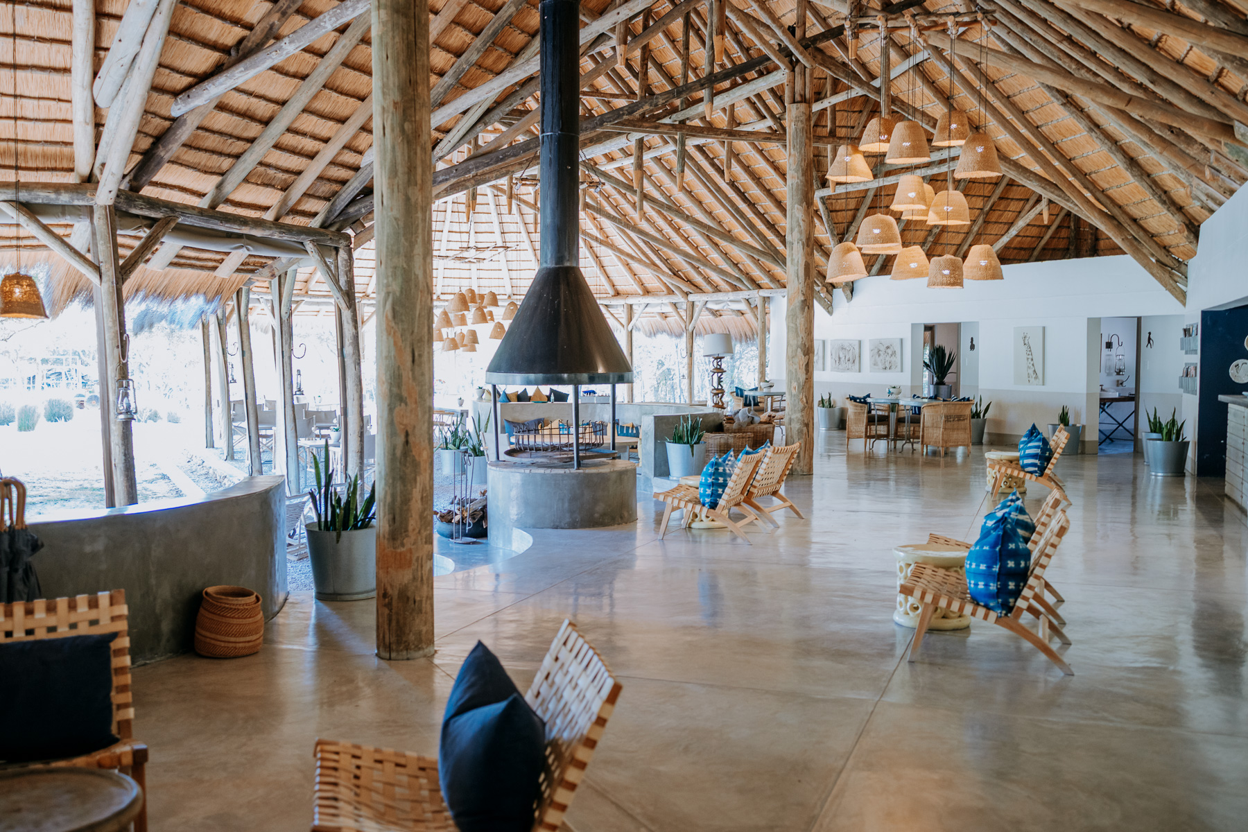 Thatched main area at Mushara Bush Camp with a central fireplace, wooden loungers and blue cushions