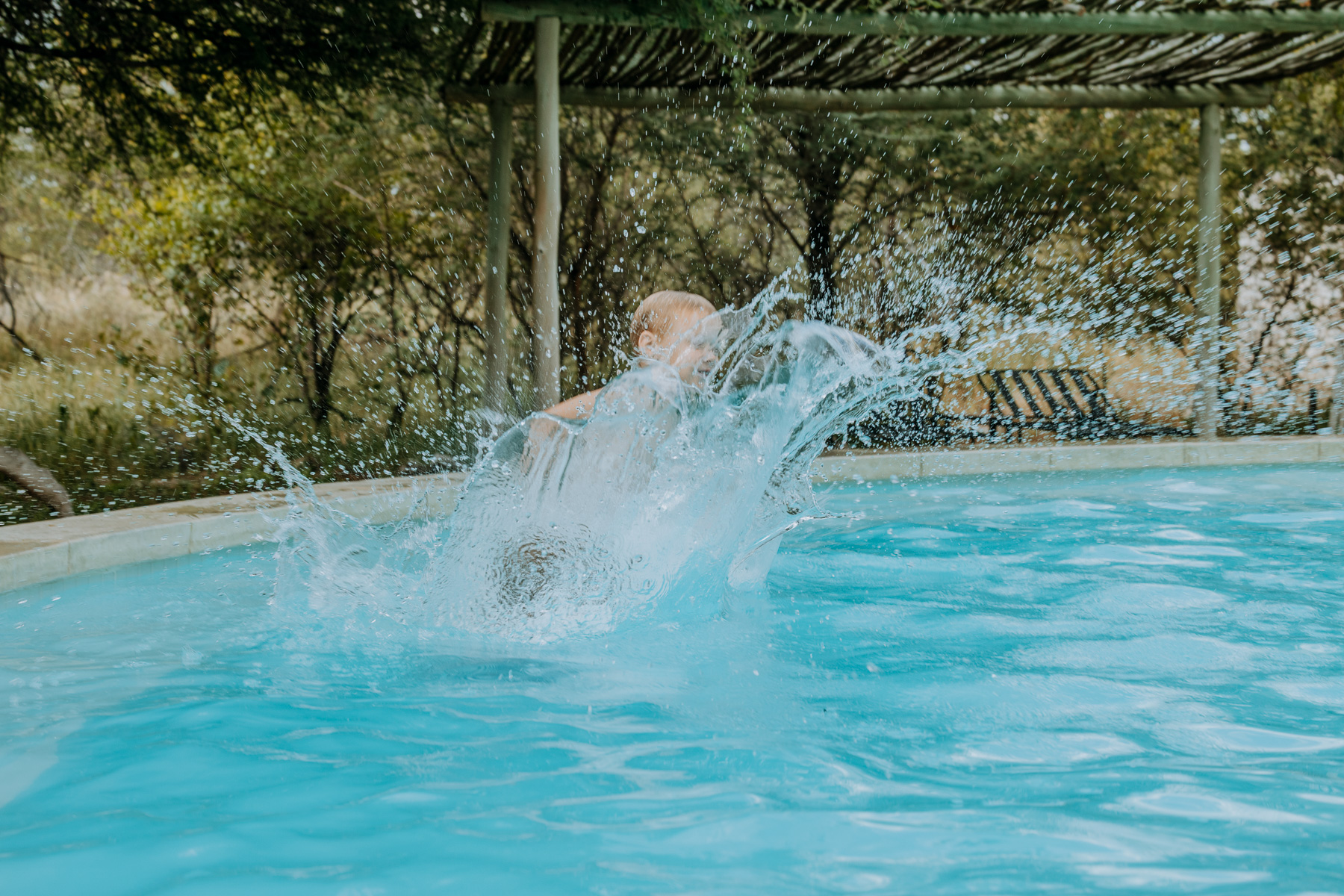 Child splashing into the swimming pool at Mushara Bush Camp near Etosha