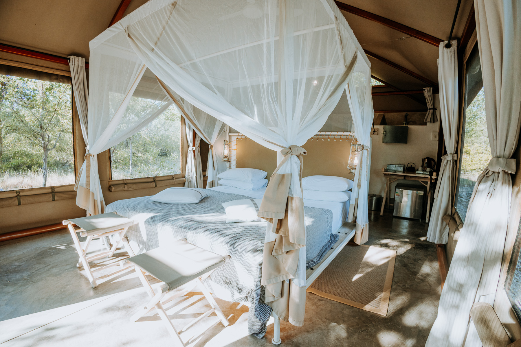 Tent at Mushara Bush Camp with a canopy bed under white mosquito netting in soft morning light