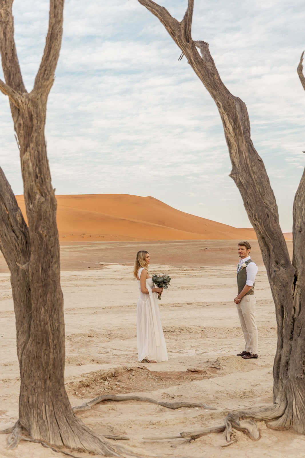 Bride and groom facing each other between the dead trees of Deadvlei