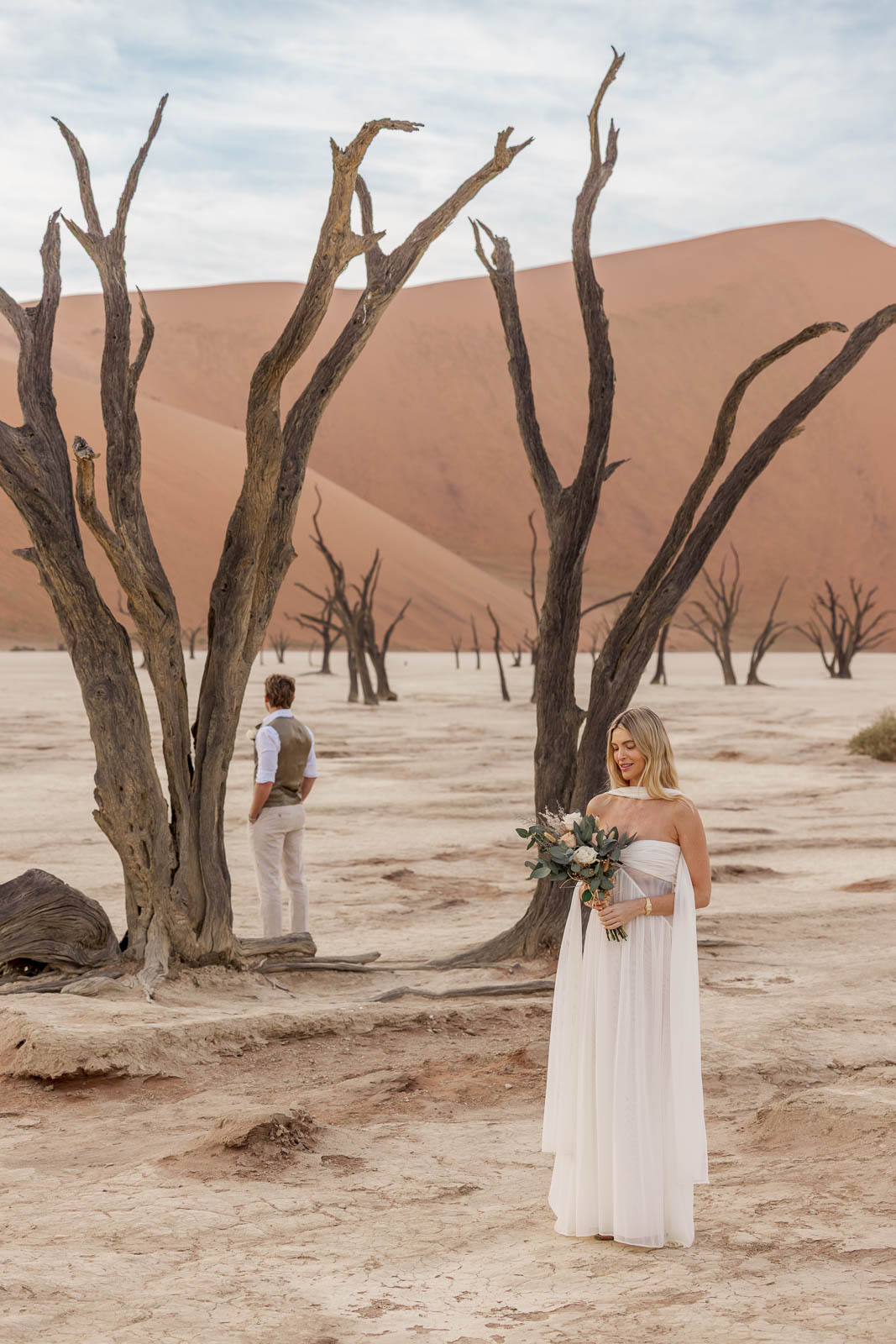 Bride walking among the dead camelthorn trees of Deadvlei on her elopement morning