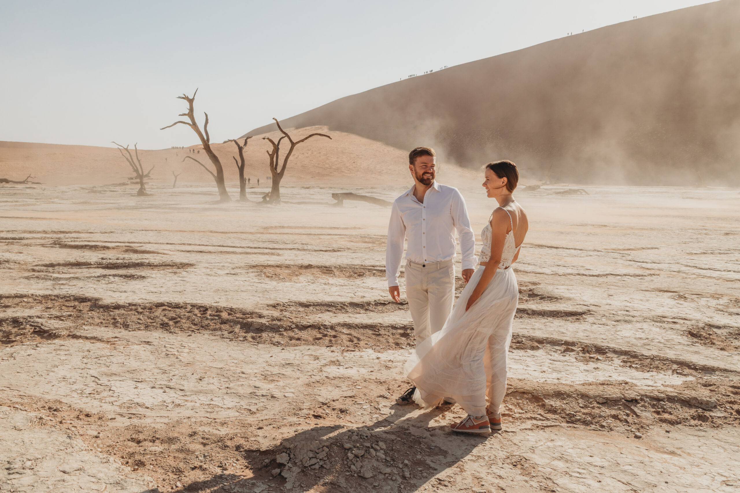 Couple walking through blowing sand in Deadvlei on a windy morning
