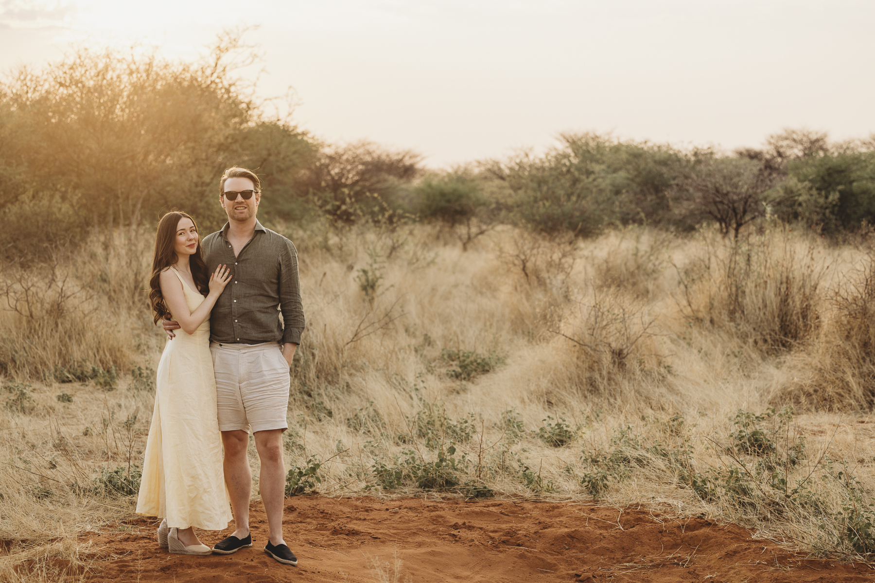 Couple standing in golden grass in the Namibian bushveld at golden hour